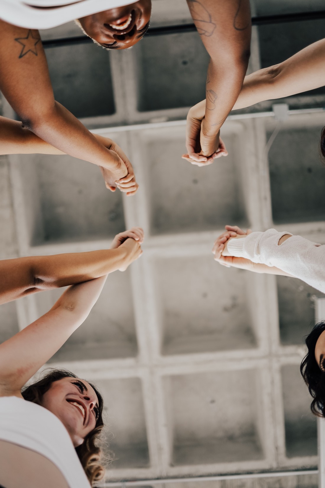 People standing in a circle holding hands and laughing, seen from below
